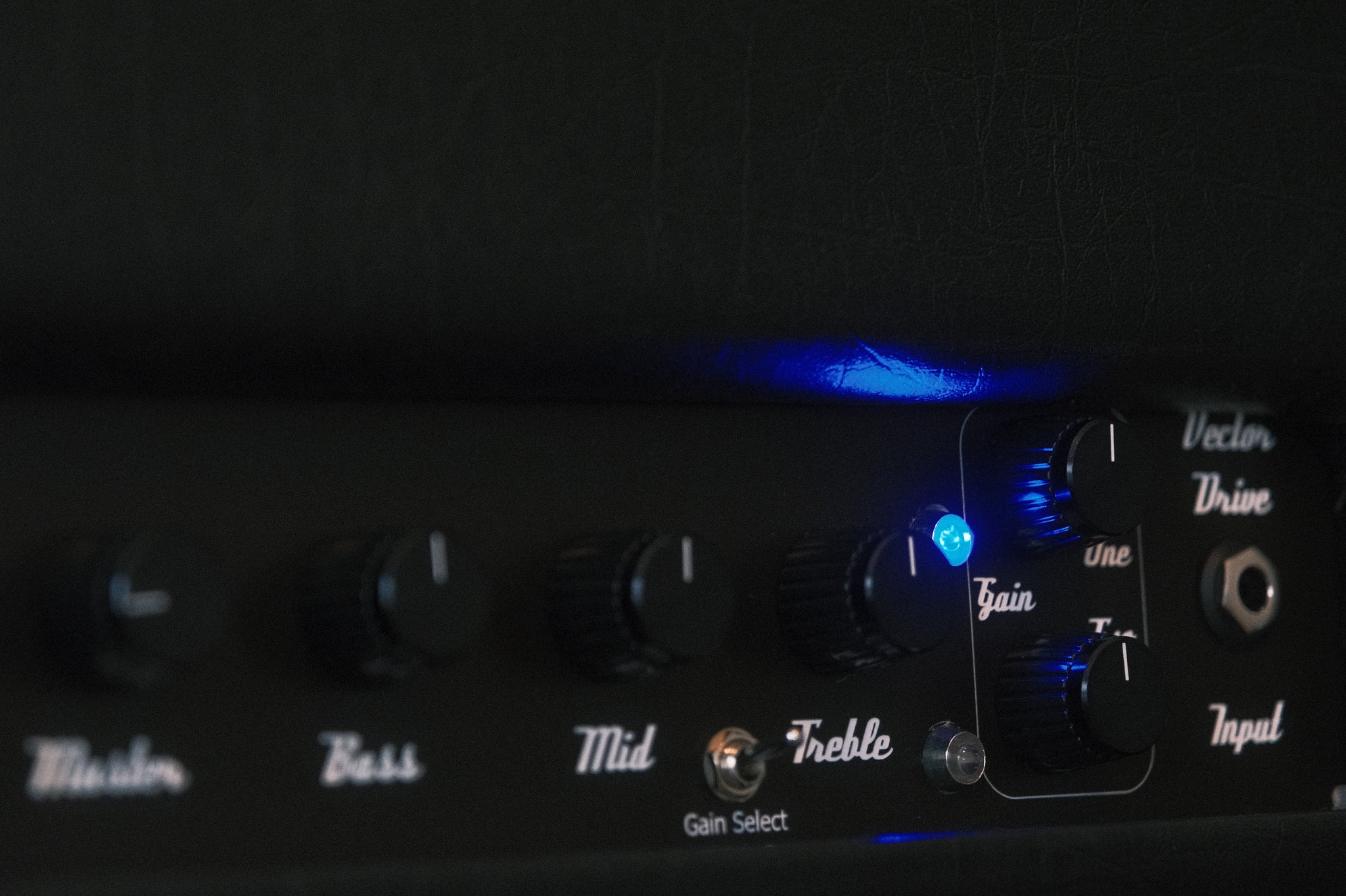 Guitar amplifier with control knobs and LED indicators on a dark background